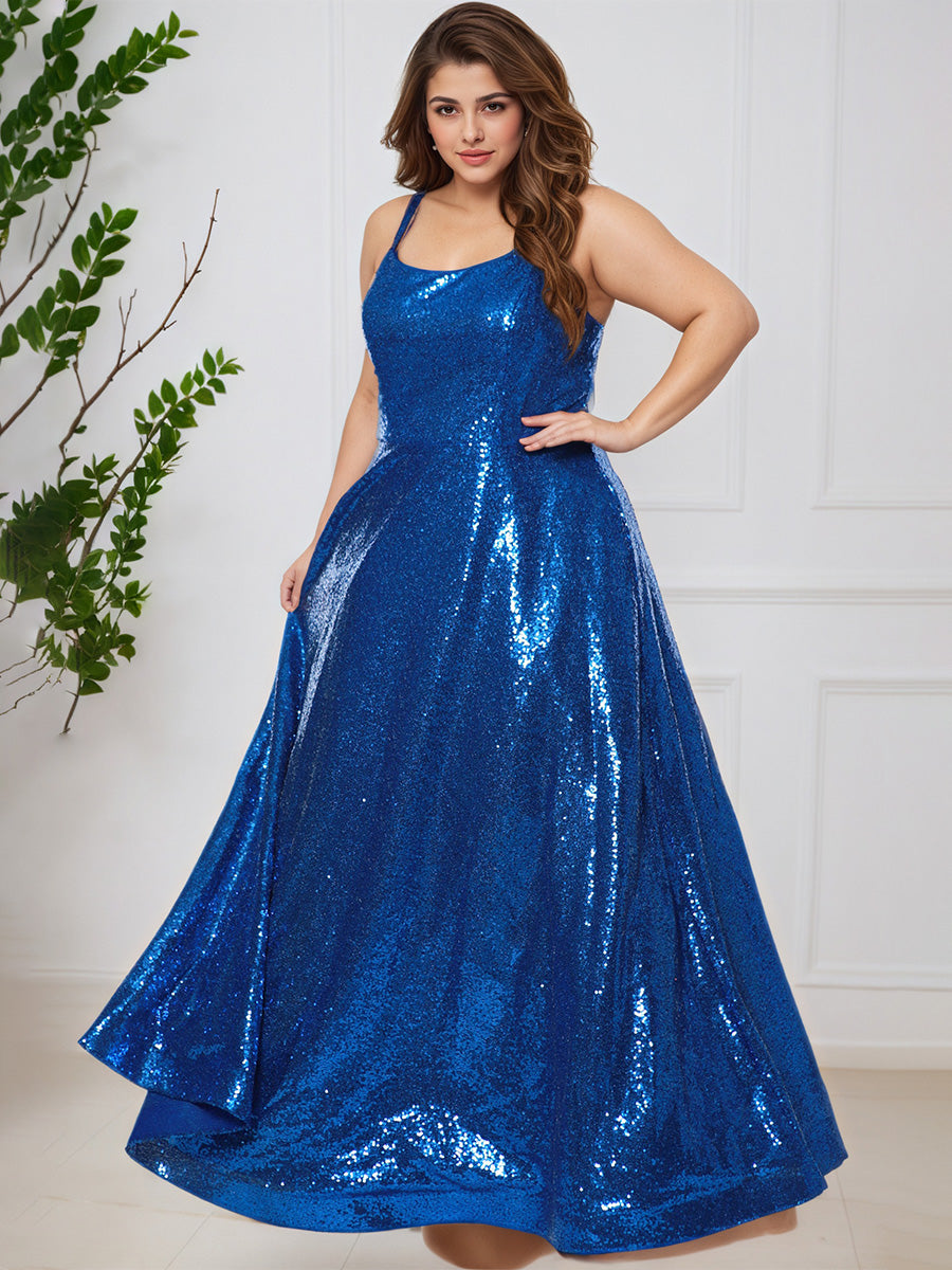 Woman wearing a blue sequin dress against a white wall with a plant on the left.