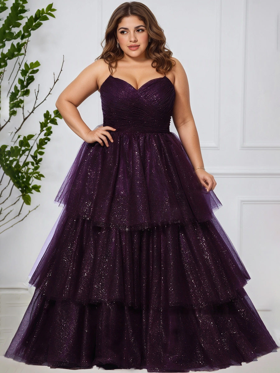 Woman wearing a grape tiered dress against a white wall with greenery.